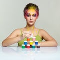 Portrait of young woman posing at the table with pyramid of small cans of paint