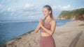 Portrait of woman practices yoga, concentrates on breathing at beach, slow motion