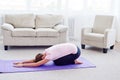 Portrait of young woman practicing yoga at home indoor, copy space. Girl relax meditation in child`s pose, full length. Royalty Free Stock Photo