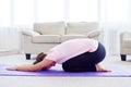 Portrait of young woman practicing yoga at home indoor, copy space. Girl relax meditation in child`s pose, full length. Royalty Free Stock Photo