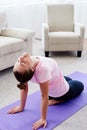 Portrait of young woman practicing yoga at home indoor, copy space. Girl stretching on mat, full length. Relaxing and doing yoga. Royalty Free Stock Photo