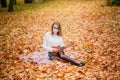 Portrait young woman in protective mask playing ukulele guitar in autumn park, healthy travel