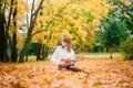 Portrait young woman in protective mask playing ukulele guitar in autumn park, healthy travel