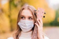 Portrait young woman in protective mask playing ukulele guitar in autumn park, healthy travel