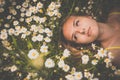 Portrait of young woman with radiant clean skin lying down amid flowers on a lovely meadow