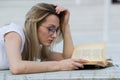 Portrait of young woman reading a book lying on the bench in the park Royalty Free Stock Photo