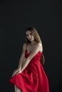 Portrait of a young woman in a red dress sitting on a high bar stool Royalty Free Stock Photo