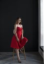 Portrait of a young woman in a red dress sitting on a high bar stool Royalty Free Stock Photo