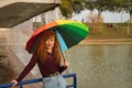 Portrait of young woman, red hair, freckles, with a rainbow umbrella, happy, in an outdoor park. Concept color, happiness, well- Royalty Free Stock Photo