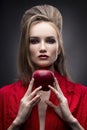 Portrait of the young woman in a red scarf with a vanguard hairstyle which holds in hand red apple on a gray background Royalty Free Stock Photo