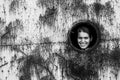 Portrait of a young woman in a round window in a rusty iron wall. Royalty Free Stock Photo