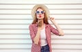 Portrait young woman sending sweet air kiss blowing red lips in summer round straw hat, checkered shirt on white wall Royalty Free Stock Photo