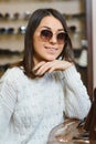 Portrait of a young woman shopping, standing in store and trying sunglasses near a mirror Royalty Free Stock Photo