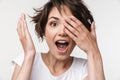 Portrait of young woman with short brown hair in basic t-shirt covering her eyes with hands Royalty Free Stock Photo