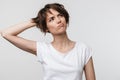 Portrait of young woman with short brown hair in basic t-shirt frowning and looking upward Royalty Free Stock Photo