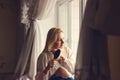 Portrait of young woman siiting near the window and combing her hair