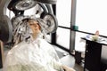 Portrait of young woman sitting in salon with hair dye applied on long hair wrapped in foil under hooded dryer machine. Royalty Free Stock Photo
