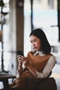 Young woman sitting on comfortable chair and using mobile phone. Royalty Free Stock Photo