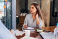 Portrait of young woman sitting at desk listening to a teacher and making notes in copybook during the lesson at college