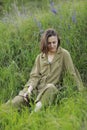 Portrait of a young woman sitting in a field on the spring grass among purple flowers. stylish girl enjoys Sunny spring Royalty Free Stock Photo