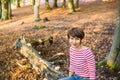 Portrait of young woman sitting and relaxing on the fallen tree in autumnal forest. looking at camera, smiling girl. Autumn Royalty Free Stock Photo