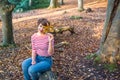 Portrait of young woman sitting and relaxing on the fallen tree in autumnal forest. looking at camera, smiling girl. Autumn Royalty Free Stock Photo