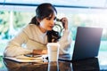 Portrait of young woman sitting at table in front of laptop. Girl works on computer cafe, checks e-mail, browses social networks Royalty Free Stock Photo