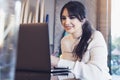 Portrait of young woman sitting at table in front of laptop. Girl works on computer cafe, checks e-mail, browses social networks Royalty Free Stock Photo