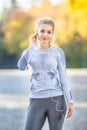 Portrait of a young woman with smartphone and headphones preparing for a jogging in autumn park Royalty Free Stock Photo