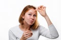 Portrait of a young woman smearing medicine on a pimple on her forehead. White background. Acne and pimples