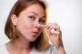 Portrait of a young woman smearing medicine on a pimple on her nose. White background. Acne and pimples concept