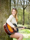 Portrait of a young woman smiling with guitar outdoors Royalty Free Stock Photo