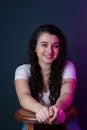 Portrait of young woman smiling sitting on a wooden stool looking at the camera Royalty Free Stock Photo