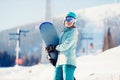 Portrait young woman snowboarder stands with snowboard background winter ski lift resort Royalty Free Stock Photo