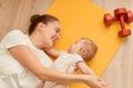 Portrait of Young woman in sports training with her toddler kid, sporty mother engaged with the child in fitness and yoga at home Royalty Free Stock Photo