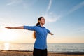 Portrait of a young woman in sportswear is warming up on the beach. The concept of outdoor sports