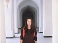 Portrait of a young woman standing in a corridor of white arabian arches in Kalyan Mosque, Bukhara, Uzbekistan