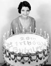 Portrait of a young woman standing in front of a birthday cake Royalty Free Stock Photo