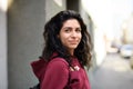 Portrait of young woman standing outdoors on street in city.