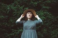 Portrait of a young woman in a straw hat and dress with closed eyes on a background of green forest and trees. Place for text or Royalty Free Stock Photo