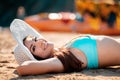 A portrait of young woman in a straw hat is lying on the sand and sunbathing. The concept of relaxing by the sea and sunbathing Royalty Free Stock Photo