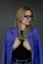 Portrait of young woman in stylish blue female blazer and glasses looking away, gray background, free copy space. New