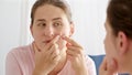 Portrait of young woman suffering from acne squeezing pimples on her cheek while looking in mirror Royalty Free Stock Photo