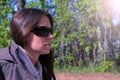 Portrait of woman in sunglasses sitting resting in forest on riverbank.