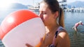 Portrait of young woman in swimsuit blowing up colorful ball at sea beach Royalty Free Stock Photo