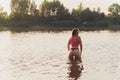 Portrait of young woman swimsuit is standing in the water in a forest lake in the sunset. Royalty Free Stock Photo