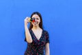 Portrait of young woman taking a picture holding a retro vintage camera on colorful background wall in summer. happy and joyful