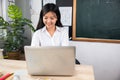 Portrait of young woman teacher with laptop at desk in classroom Royalty Free Stock Photo