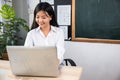 Portrait of young woman teacher with laptop at desk in classroom Royalty Free Stock Photo
