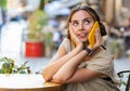 Happy woman having remote conversation talking on smartphone, good news gossip in city cafeteria Royalty Free Stock Photo